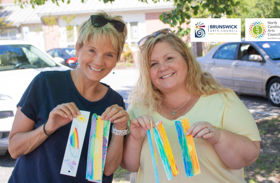 Two women holding art projects they created