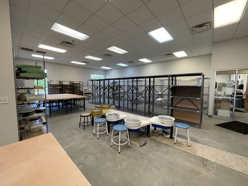 Studio space with pottery equipment and shelves.