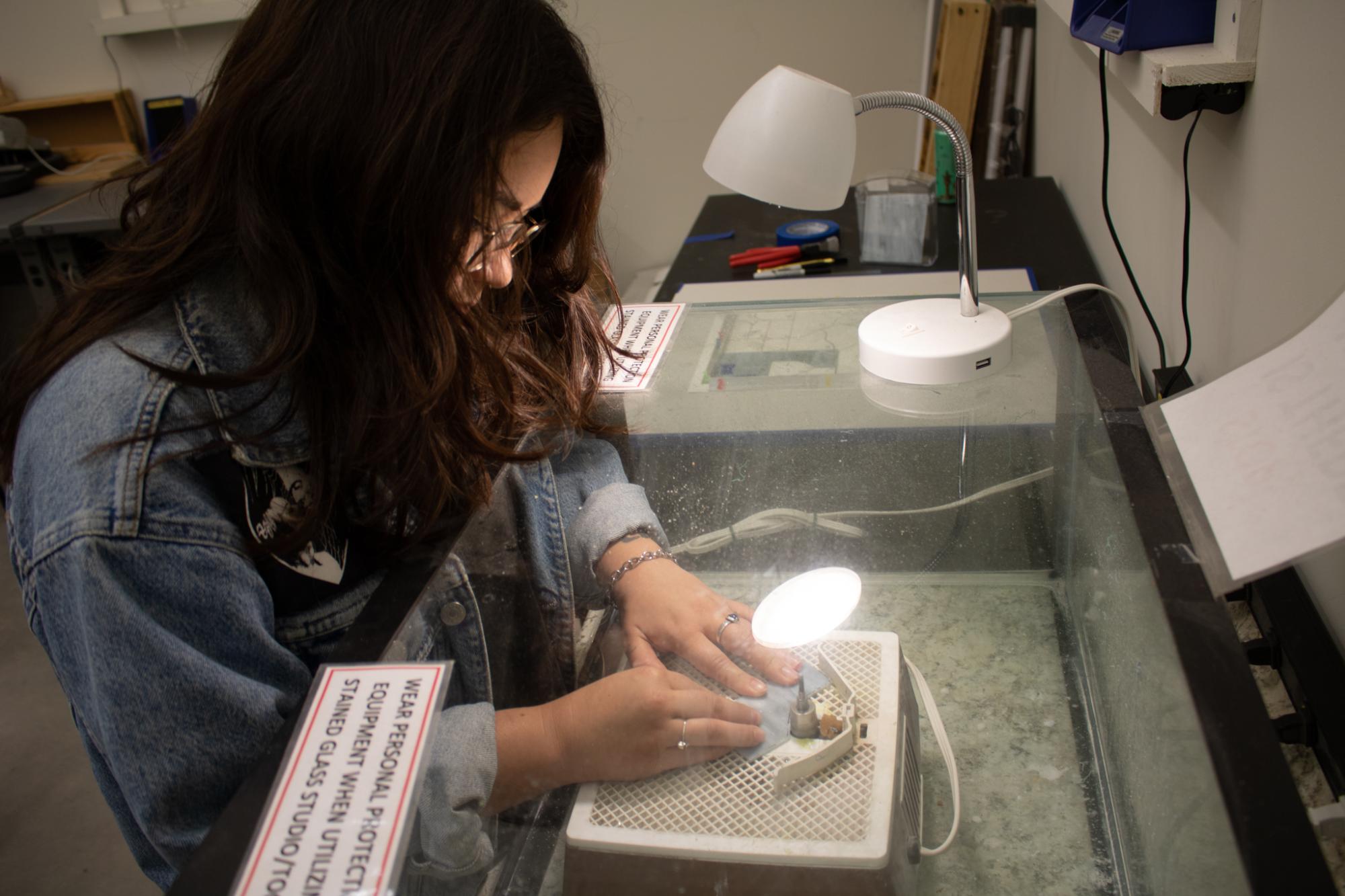 Person using stained glass equipment.