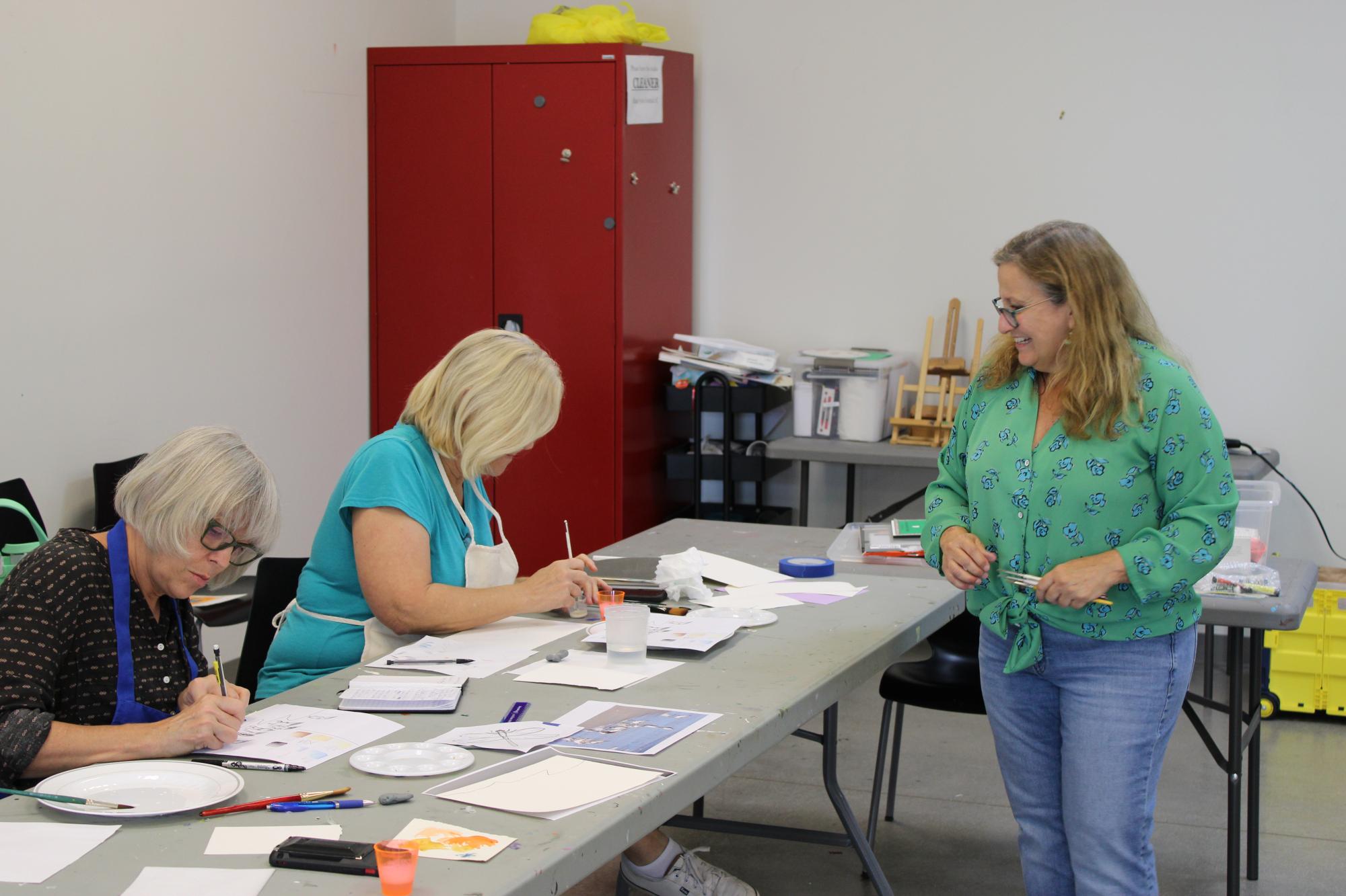 Instructor walking around as participants paint with watercolors