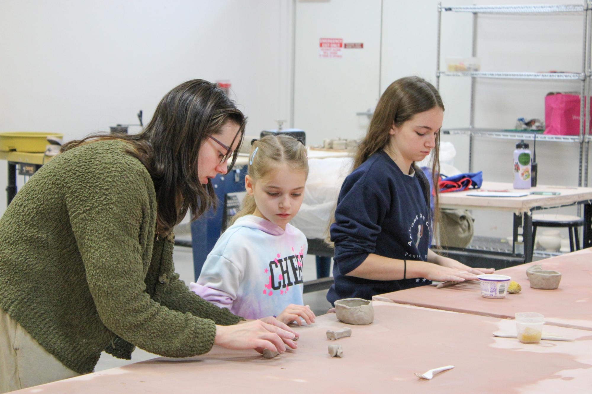 Instructor assisting students with their clay.