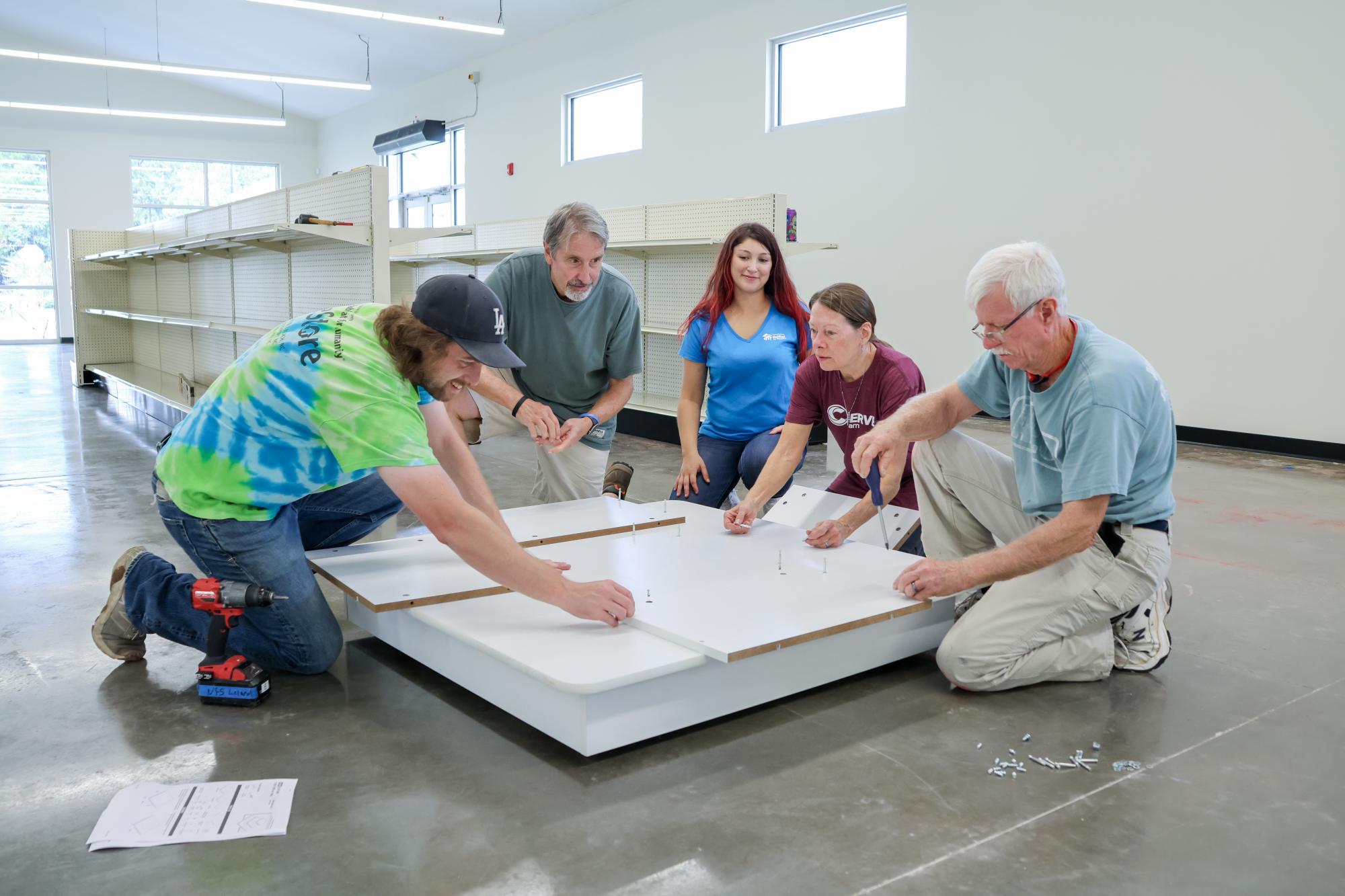 Five people kneeling beside a workspace